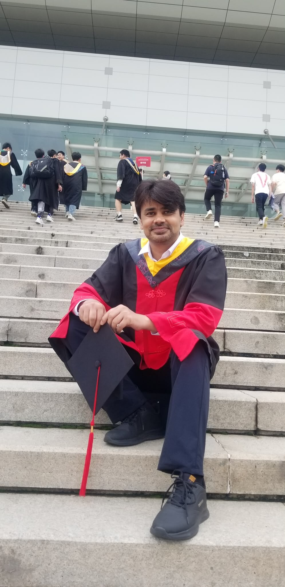 Dr Naimat Ullah Khan seated on university steps in doctoral graduation regalia