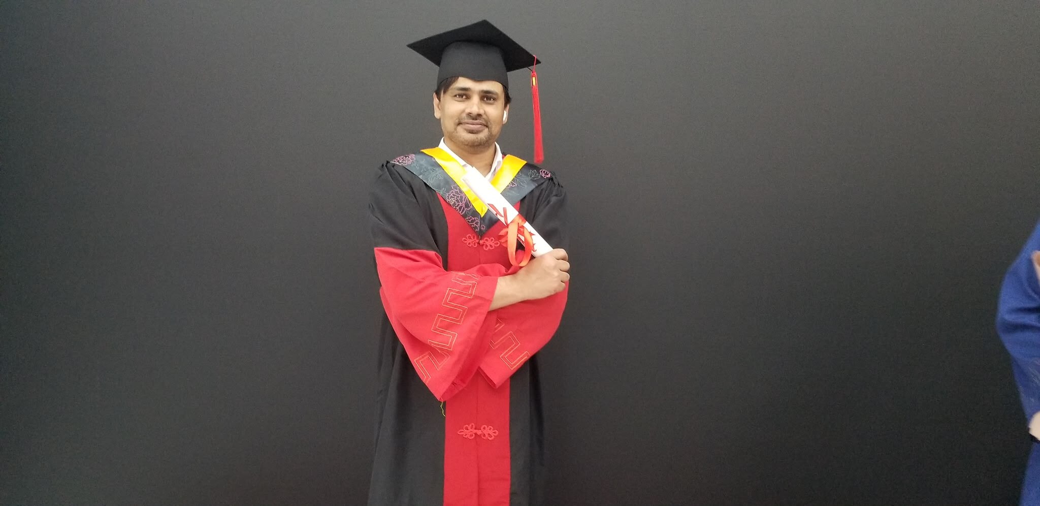 Dr Naimat Ullah Khan standing in doctoral graduation regalia